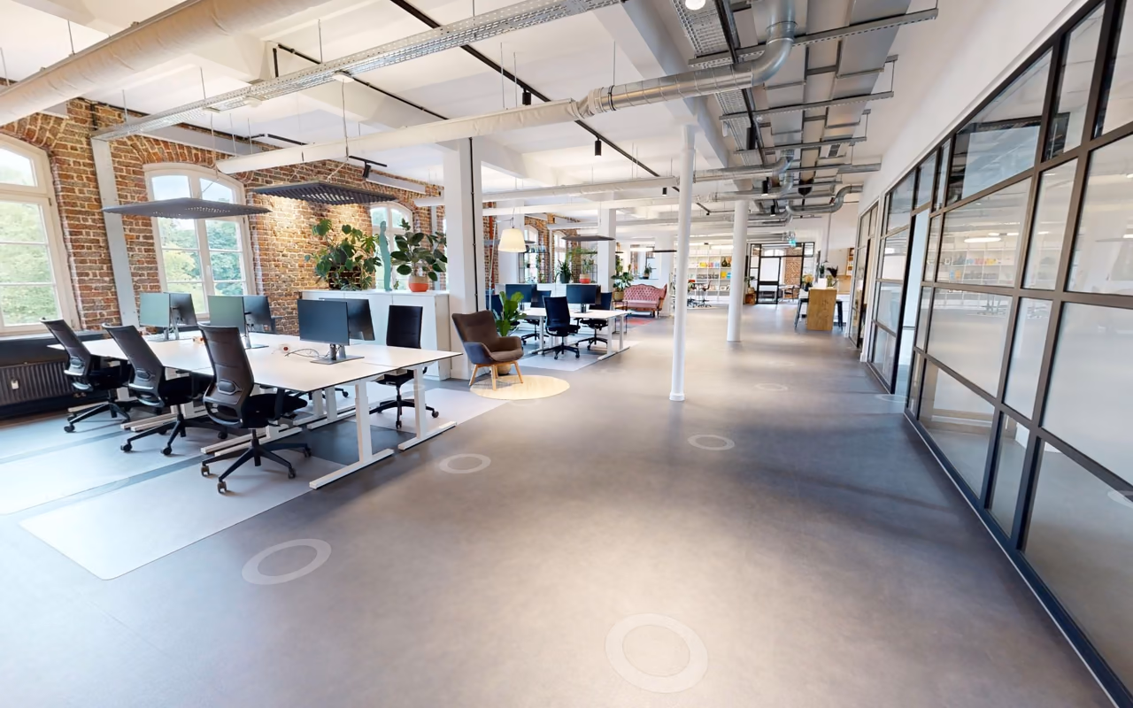 Innenansicht des Rundgangs StartMiUp mit Arbeitsplätzen, Backsteinwand und runden Scanpunkten am Boden