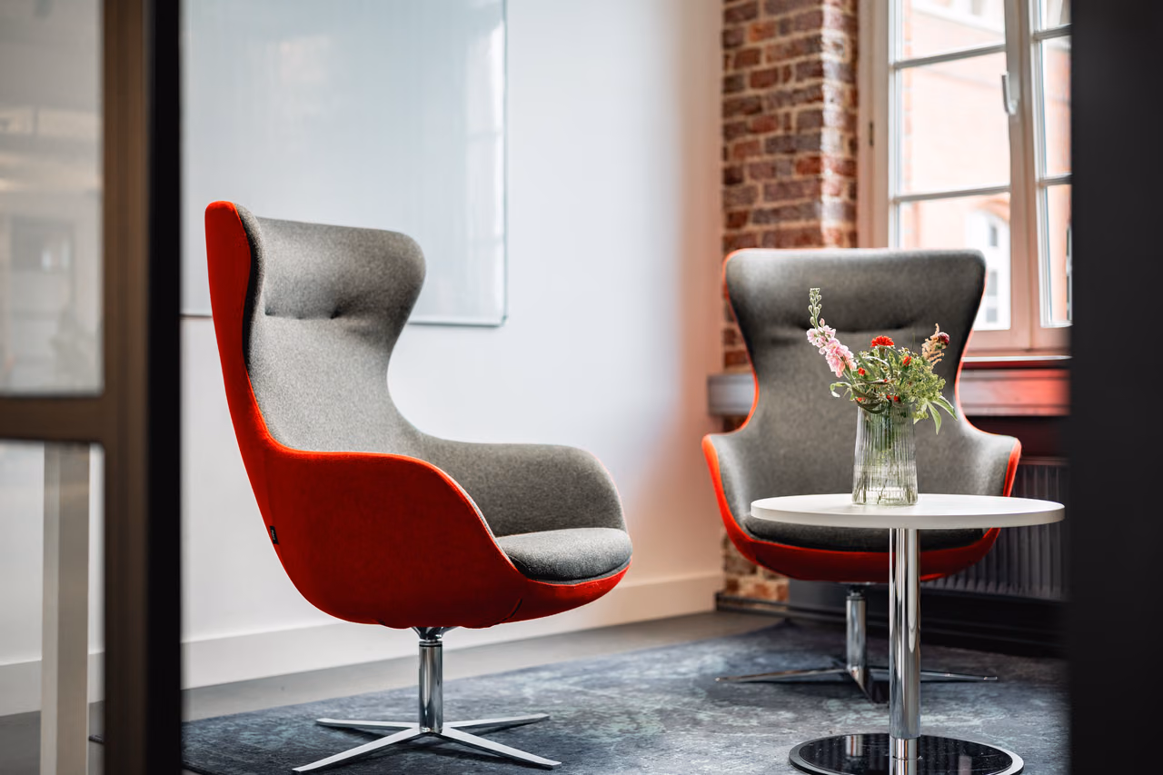Zwei Sessel mit Beistelltisch und Blumen in der Lounge von StartMiUp Minden