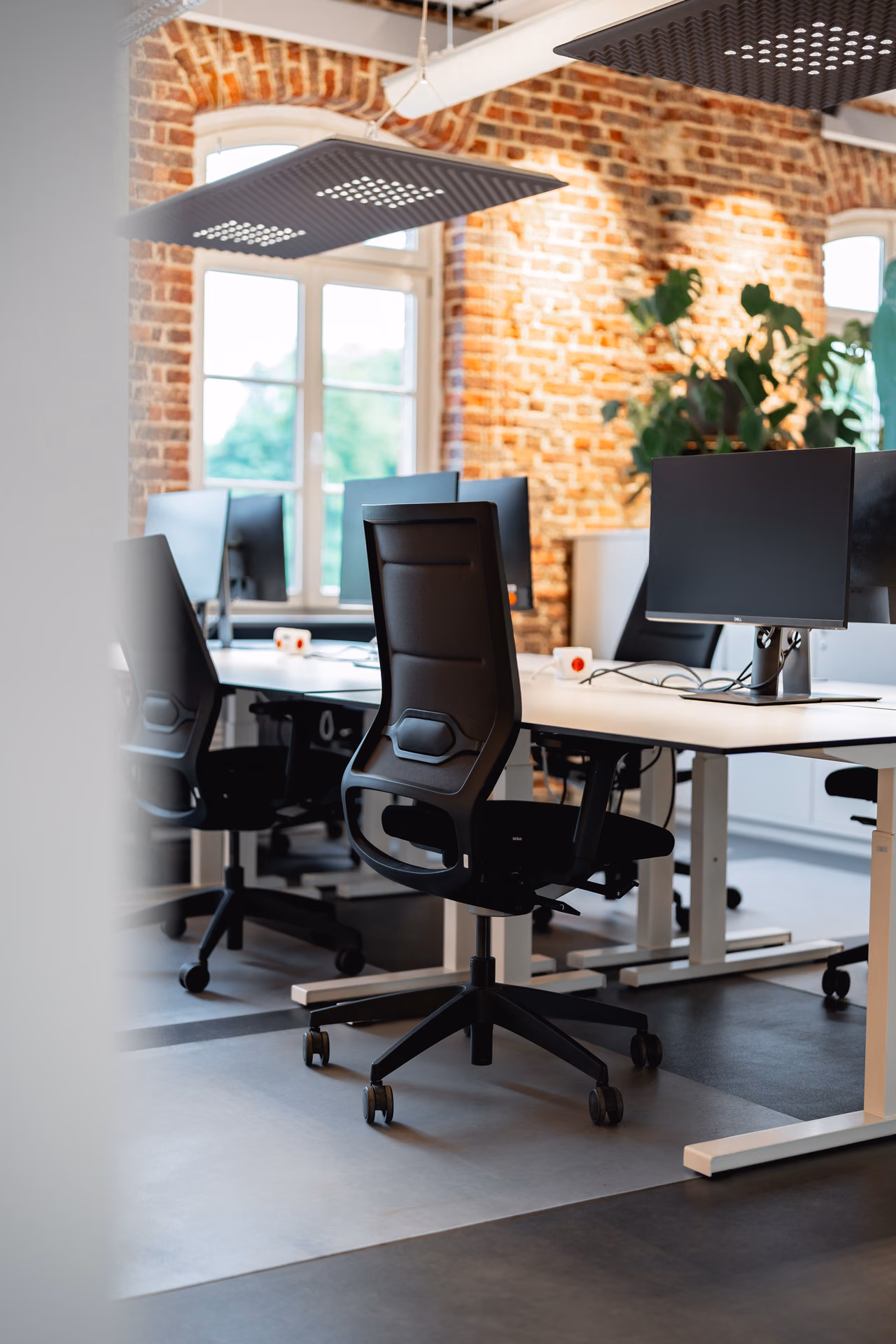 Arbeitsplatz mit Bildschirm vor Backsteinwand und Fenster
