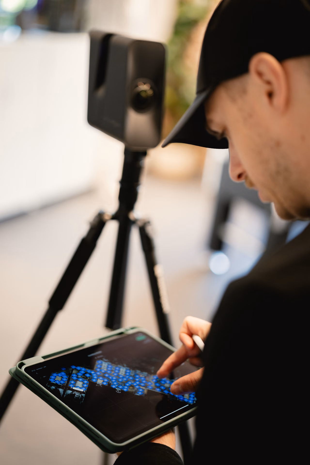 René Röbke setzt Scanpunkte auf dem iPad, dahinter die 3D-Kamera auf dem Stativ